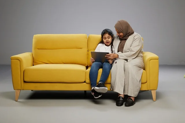 Arab Mother and Daughter with Tablet on Yellow Sofa