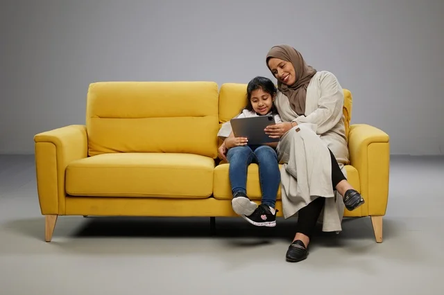 Arab Mother and Daughter with Tablet on Yellow Sofa
