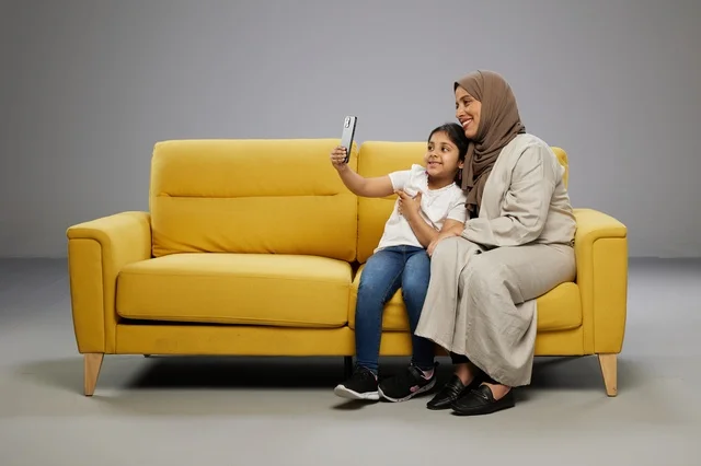 أم وابنتها تلتقطان سيلفي على أريكة صفراء