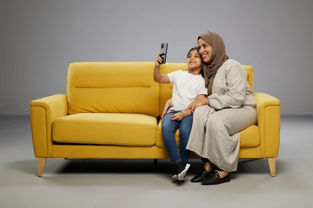 أم وابنتها تلتقطان سيلفي على أريكة صفراء