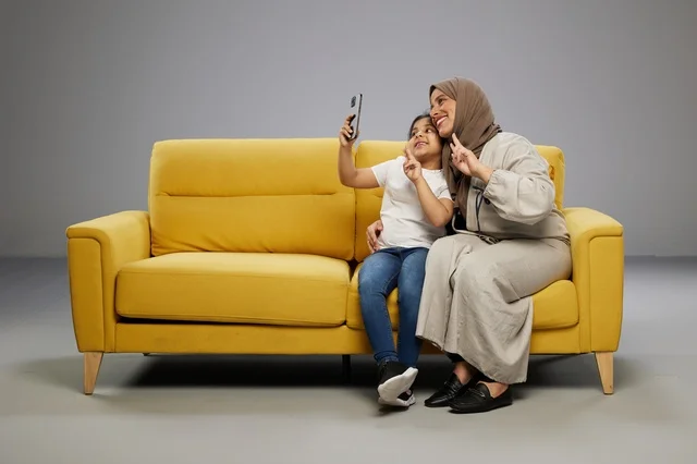 Saudi Mother and Daughter Taking Selfie on Yellow Sofa