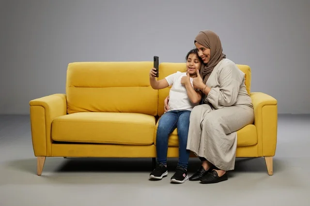 أم وابنتها تلتقطان سيلفي على أريكة صفراء