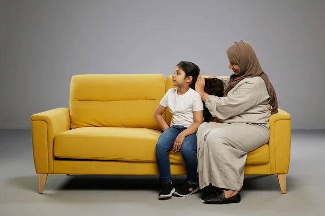 Saudi Mother Combing Daughter Hair on Yellow Sofa