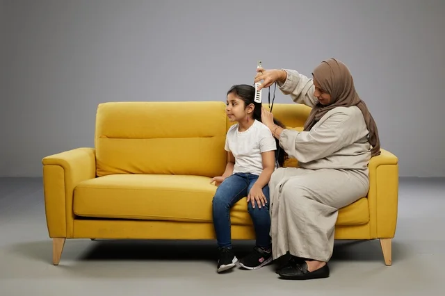 Saudi Mother Combing Daughter's Hair on Yellow Sofa