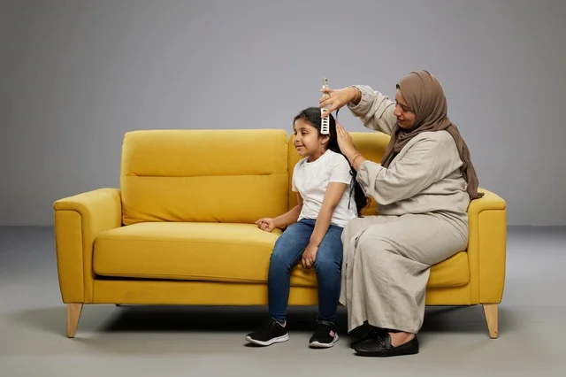 Saudi Mother Brushing Daughter's Hair on Yellow Sofa
