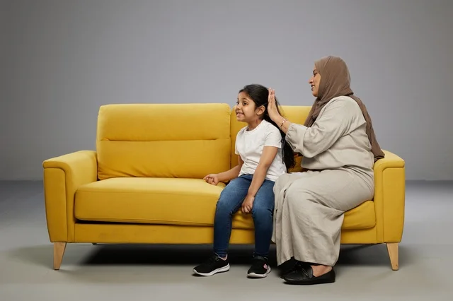 أم سعودية تمشط شعر ابنتها على أريكة صفراء