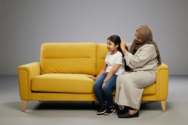 Saudi Mother Combing Daughter Hair on Yellow Sofa