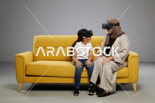 أم وابنتها تستخدمان نظارات الواقع الافتراضي على أريكة