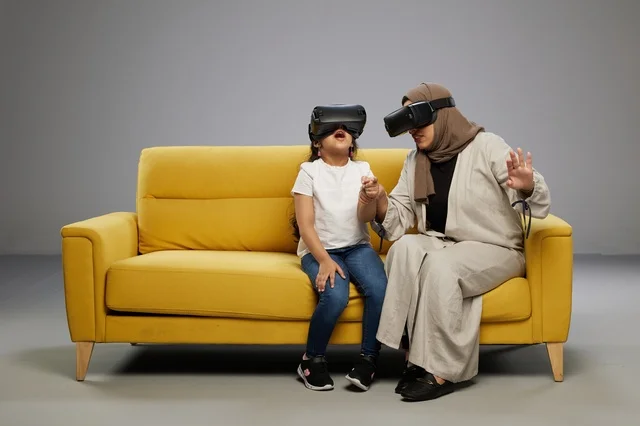 Arab Mother and Daughter Wearing VR Headsets on Sofa