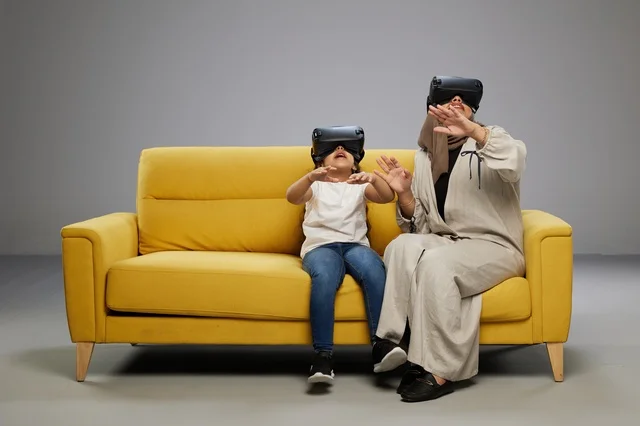 Arab Mother and Daughter Using VR Headsets on Sofa