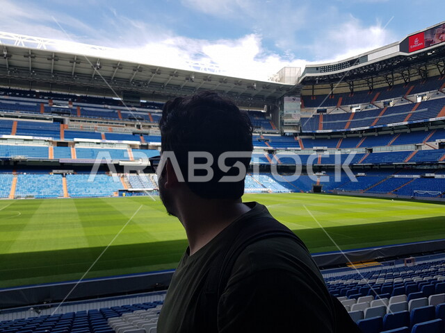 صورة من الخلف لسائح عربي خليحي من داخل ملعب ريال مدريد الجميل، ملعب البرنابيو، مدرجات الجماهير، ملعب عشبي، استاد رياضي