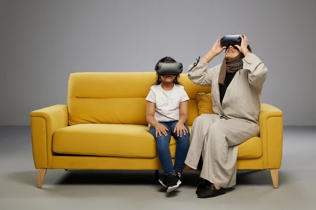Arab Mother and Daughter Using VR Headsets on Sofa