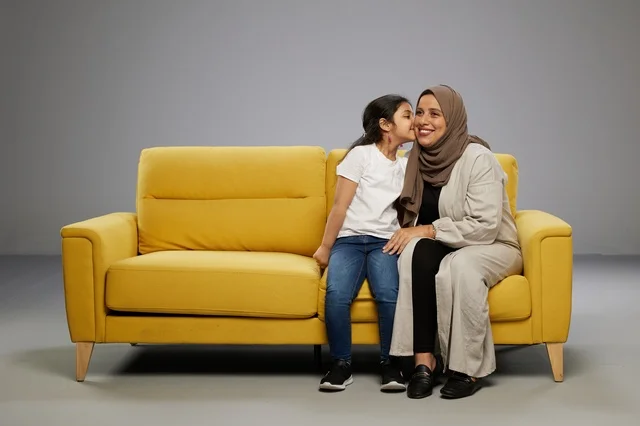 أم وابنتها على أريكة صفراء في الاستوديو