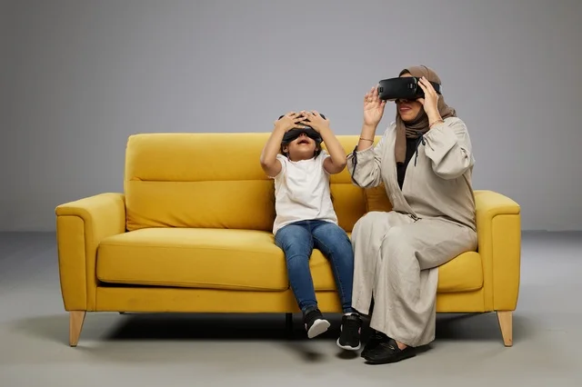 Saudi Mother and Daughter Using VR Headset on Sofa