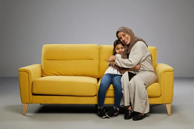 أم وابنتها سعوديتان تجلسان على أريكة صفراء
