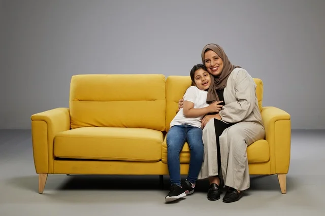 أم سعودية وابنتها تجلسان على أريكة صفراء