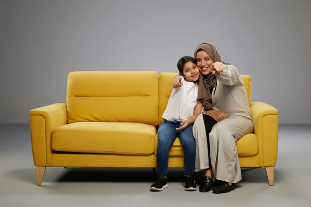 أم وابنتها تجلسان على أريكة صفراء في استوديو