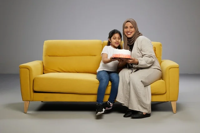أم سعودية وابنتها مع كعكة عيد ميلاد على الأريكة