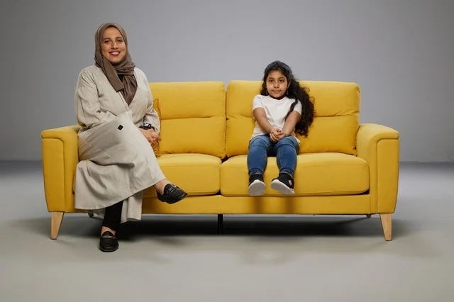 Saudi Mother and Daughter on Yellow Sofa Studio Shot