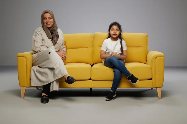 أم وابنتها سعوديات تجلسان على أريكة صفراء أم وابنتها سعوديات تجلسان على أريكة صفراء