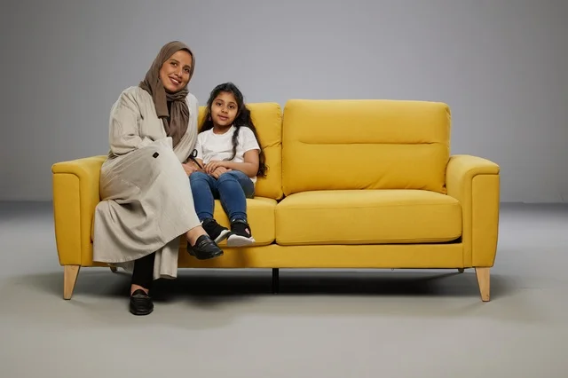 Saudi Mother and Daughter Sitting on Yellow Sofa