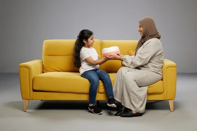 أم عربية تقدم كعكة لابنتها على أريكة صفراء
