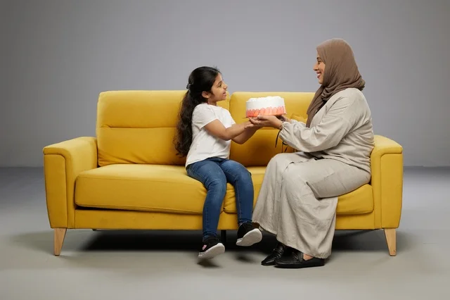 أم سعودية تقدم كعكة لابنتها على أريكة صفراء