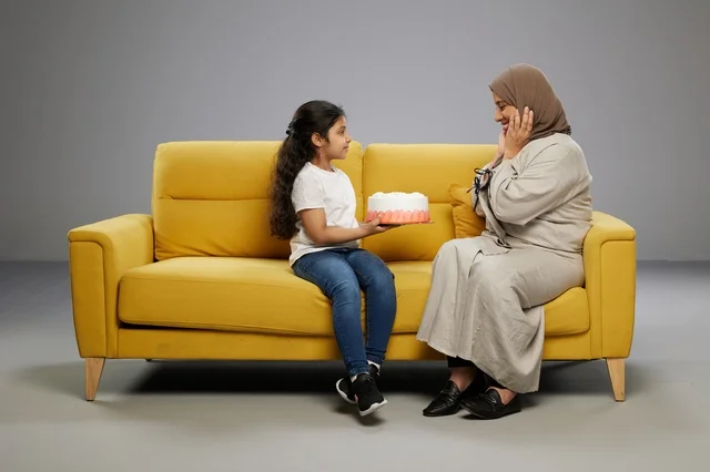 أم سعودية وابنتها مع كعكة على أريكة صفراء أم سعودية وابنتها مع كعكة على أريكة صفراء