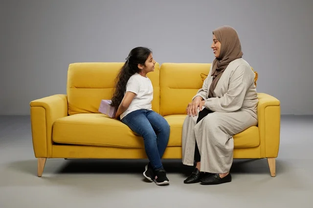 Arab Girl Hiding Gift for Mother on Yellow Sofa