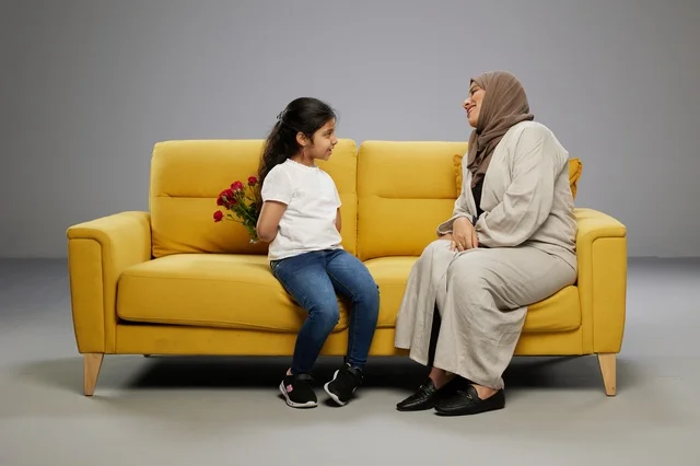 Arab Girl Hiding Red Roses for Mother on Yellow Sofa