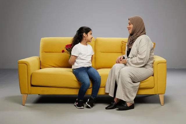 طفلة عربية تخفي الورود لوالدتها على أريكة صفراء