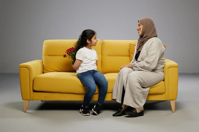 طفلة عربية تخفي الورد لوالدتها على أريكة صفراء