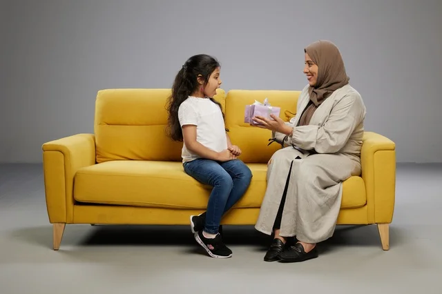 أم عربية تقدم هدية لابنتها على أريكة صفراء