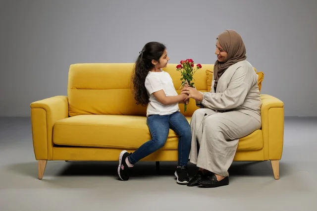 طفلة عربية تقدم ورد أحمر لوالدتها على أريكة