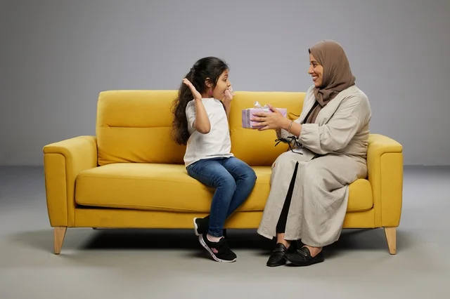 أم عربية تقدم هدية لابنتها على أريكة صفراء أم عربية تقدم هدية لابنتها على أريكة صفراء