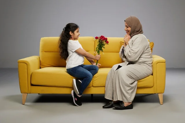 Arab Girl Giving Red Roses to Mother on Yellow Sofa Studio