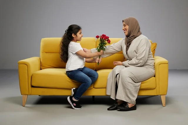 Arab Girl Giving Red Roses to Mother on Sofa