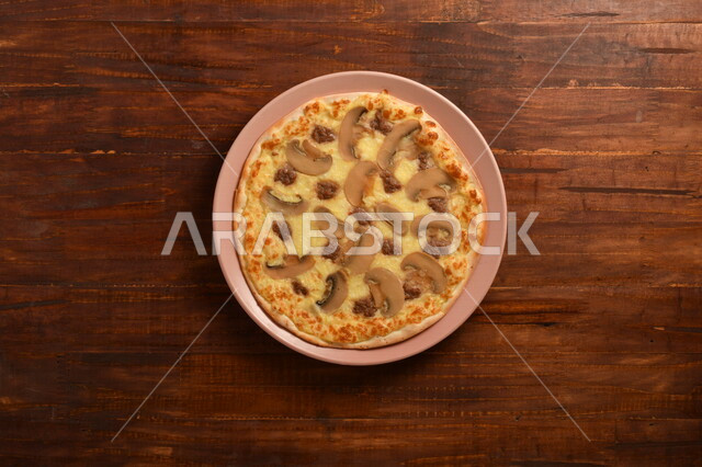 A delicious and delicious breakfast plate, a round pizza made of mushrooms and a lot of liquid cheese, many ingredients scattered next to the plate, delicious baked goods, a wooden surface