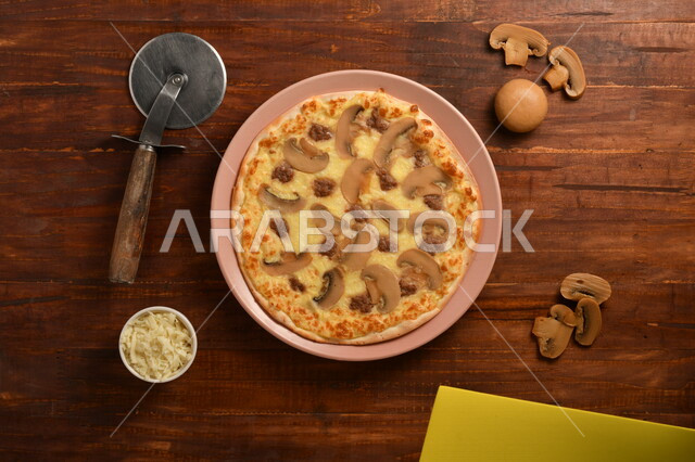 A delicious and delicious breakfast plate, a round pizza made of mushrooms and a lot of liquid cheese, many ingredients scattered next to the plate, delicious baked goods, a wooden surface