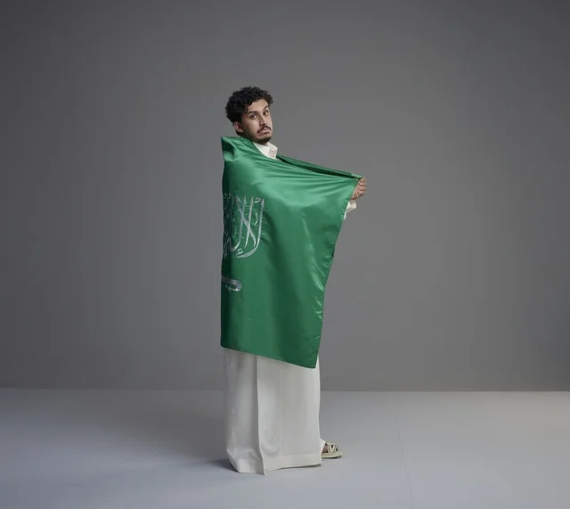 شاب سعودي يرتدي العلم الوطني في استوديو