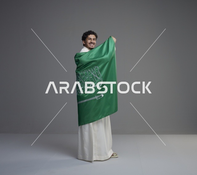 شاب سعودي يلتف بالعلم الوطني السعودي بالثوب