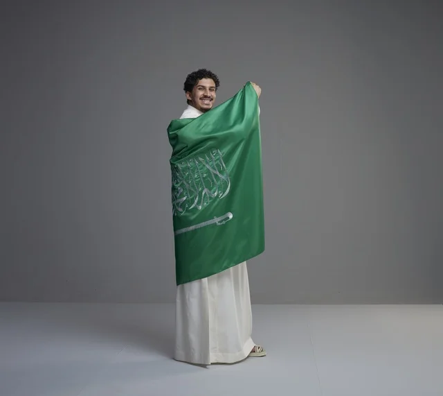 شاب سعودي يلتف بالعلم الوطني السعودي بالثوب