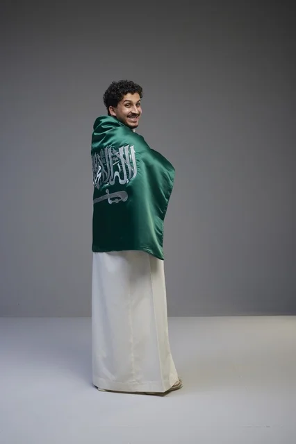 شاب سعودي يلتف بالعلم الوطني السعودي بالثوب