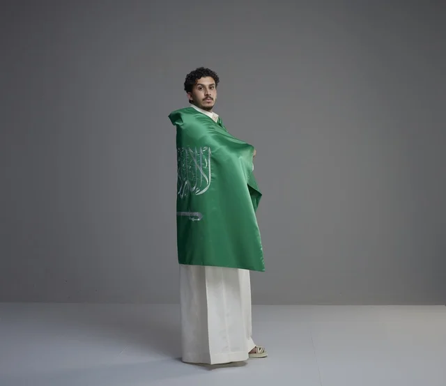 شاب سعودي يلتف بالعلم الوطني في الاستوديو