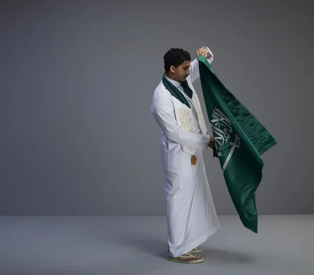 شاب سعودي يحمل العلم الوطني السعودي في الاستوديو