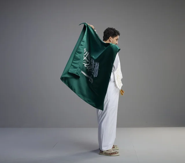 شاب سعودي يحمل العلم الوطني السعودي في الاستوديو