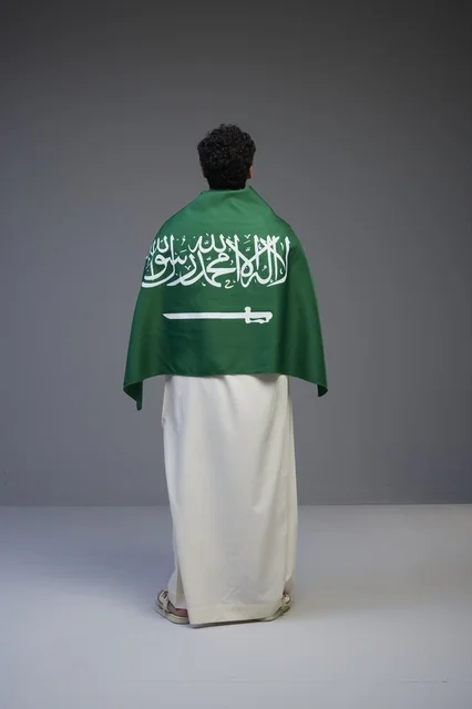 شاب سعودي يرتدي العلم الوطني السعودي من الخلف