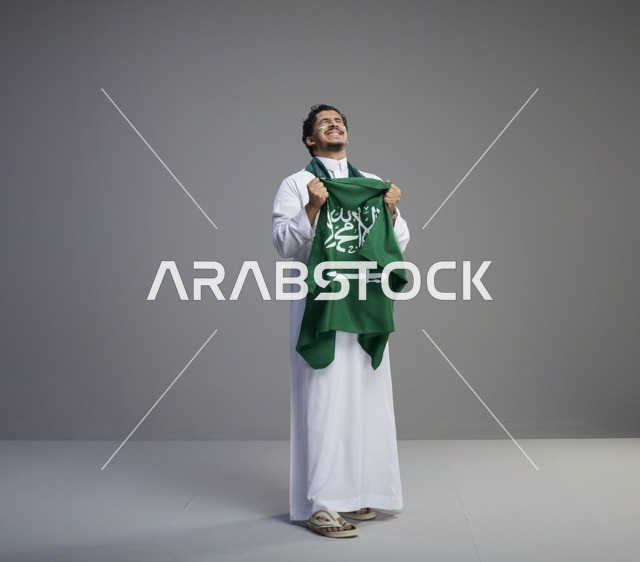 شاب سعودي يحمل العلم السعودي في الاستوديو