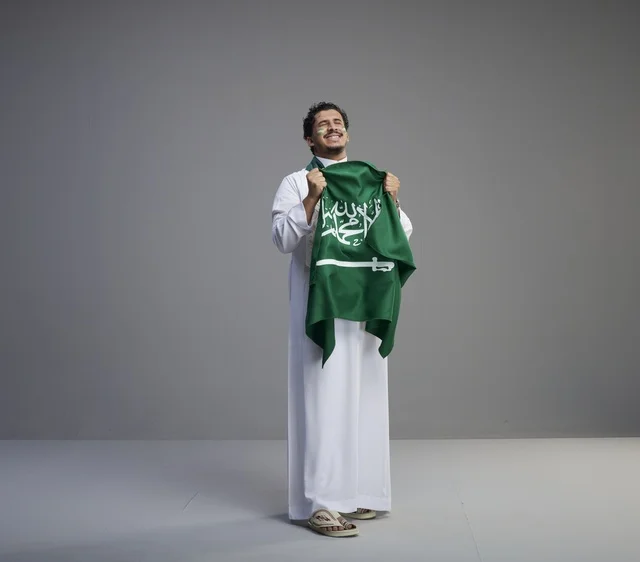 Smiling Saudi Man Holding National Flag in Studio