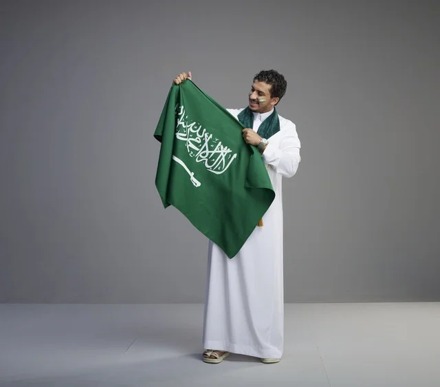 شاب سعودي يحمل العلم الوطني في استوديو